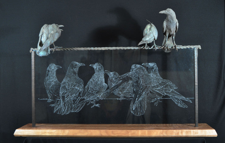 bronze sculptures of ravens atop a glass etching of ravens